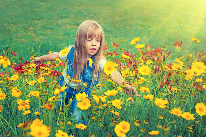 Little Girl Playing in a Field of Flowers